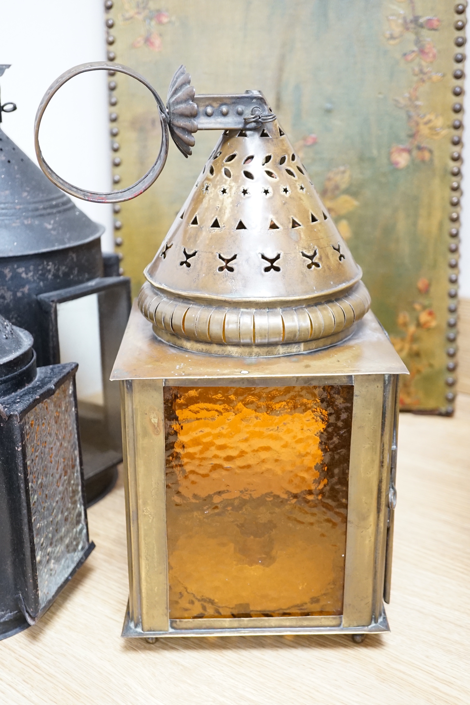 Three 19th century candle lanterns, one brass 45cm high, two black painted steel 45cm & 35cm high